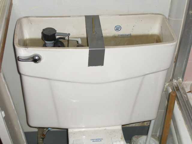 Photo of an open toilet water supply tank with a duck tape strap across the top of the tank.